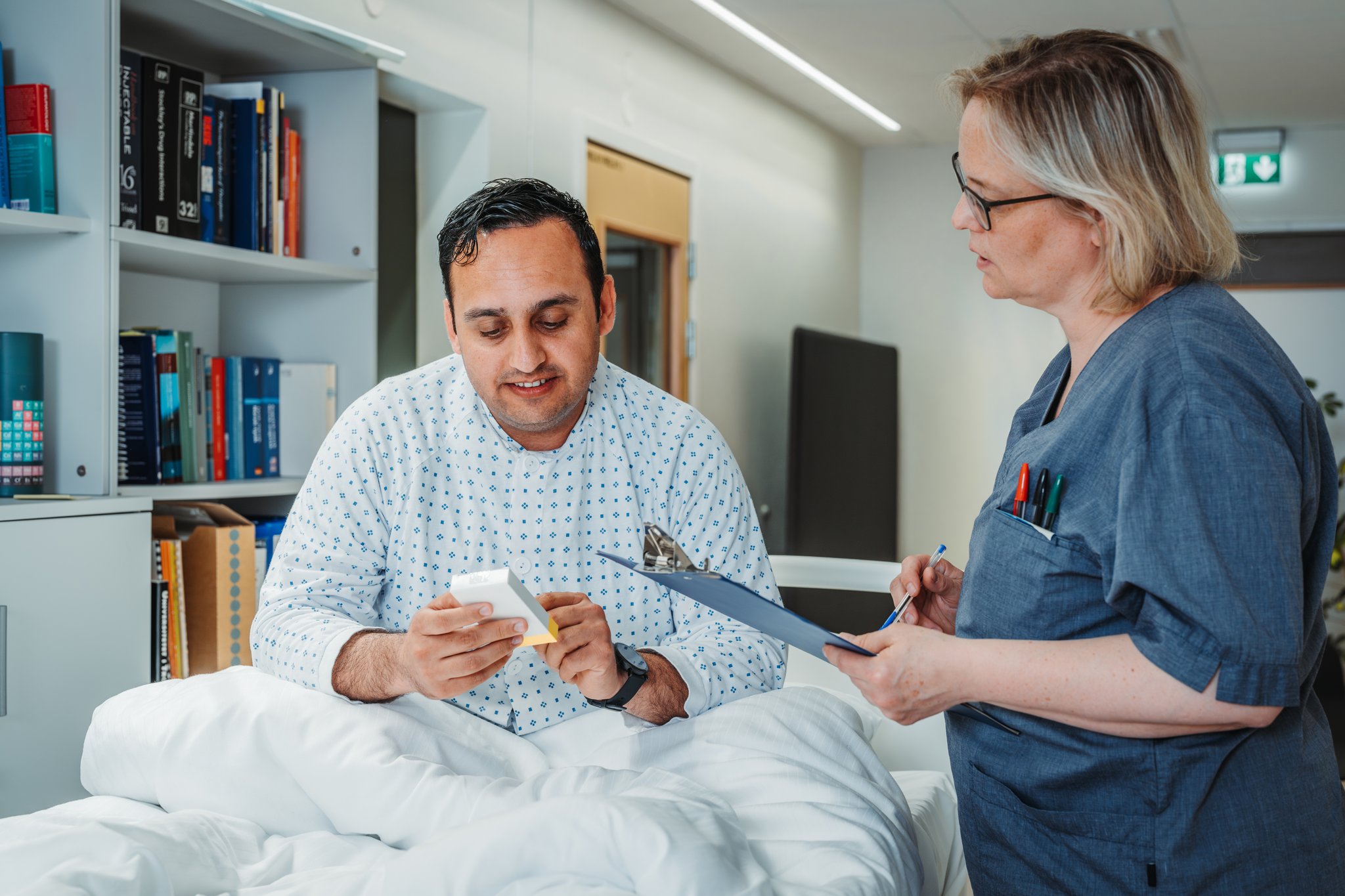 En lege som viser en pasient noe på nettbrettet